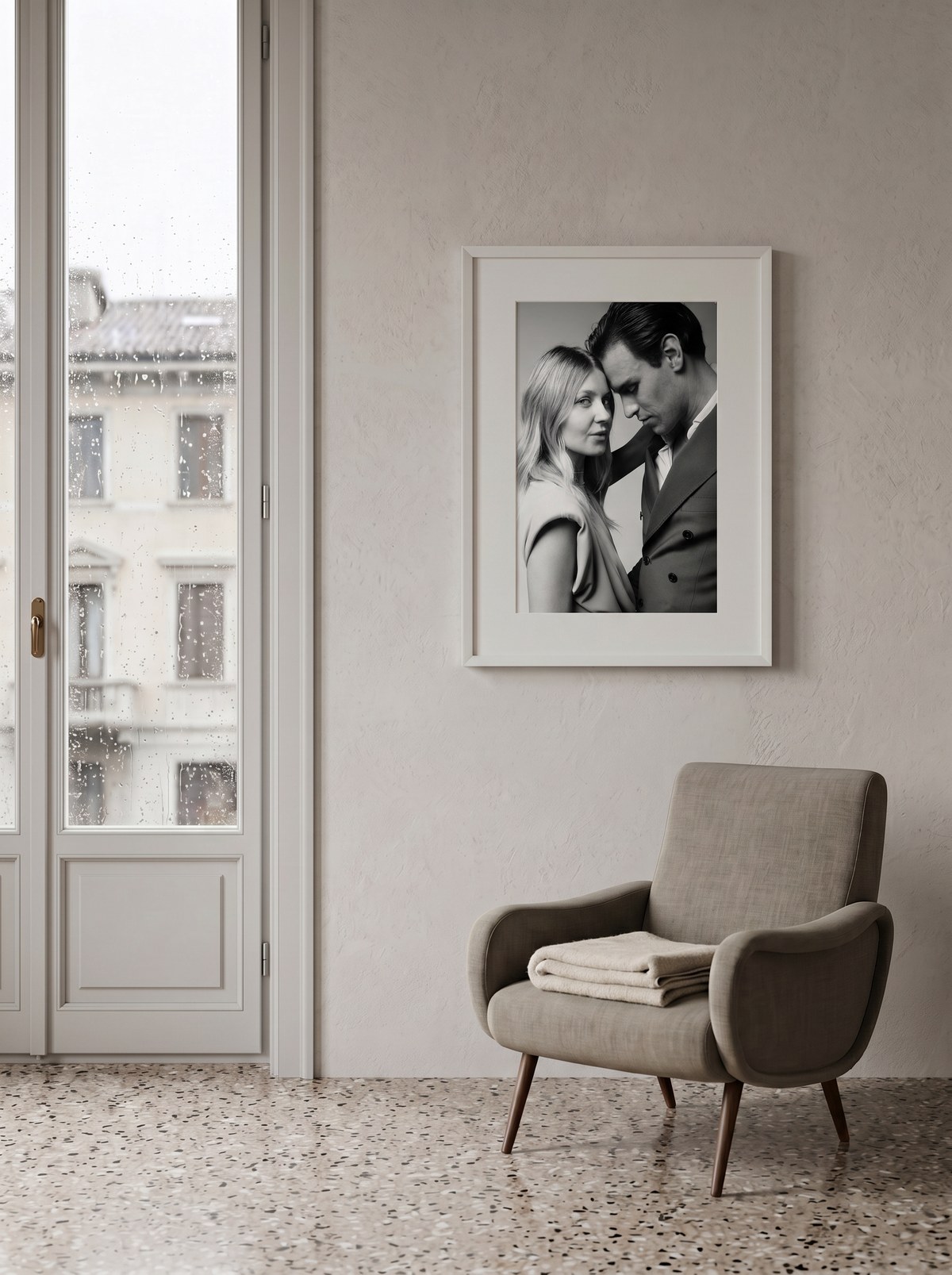 Ritratto di coppia Magneti® in cornice bianca appesa accanto a una finestra milanese, poltrona in lino e pavimento alla veneziana